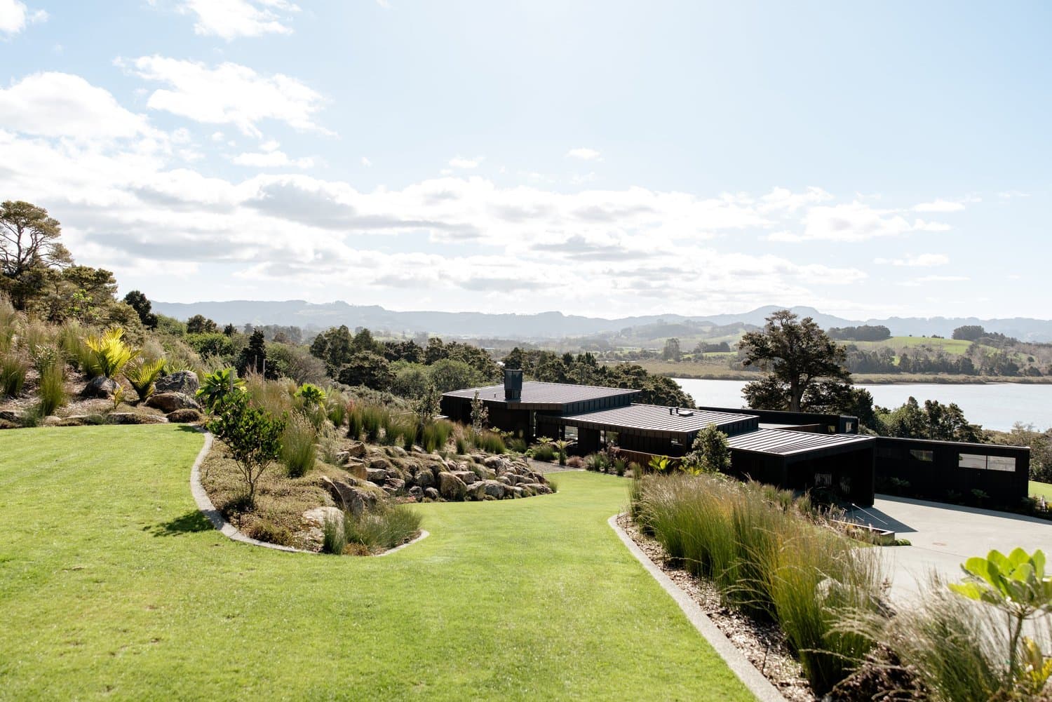 Landscaped lawn and planted slopes around a house overlooking the water